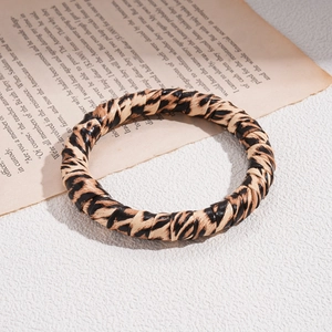 Close-up of vintage leopard print resin bangle on a classic newspaper background