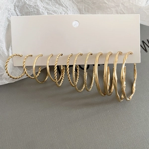 Detailed set of six pairs of gold twisted hoop earrings with varied textures on a card