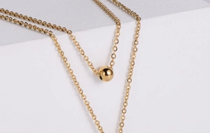 Close-up of minimalist gold polished bead pendant on a fine link chain jewelry set