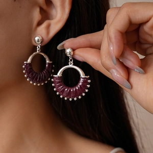 Detail of silver geometric hoop earrings with purple leather wrap and small silver beads