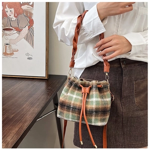 Detail of green and brown checkered wool bucket bag with a brown braided strap