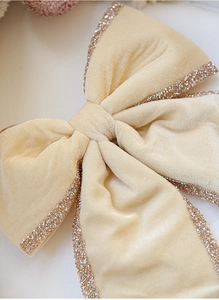 Close-up of beige velvet Christmas bow with sparkling glitter edges for tree decoration