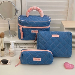 Three-piece denim blue quilted makeup bag set with pink zippers and Melody embroidery