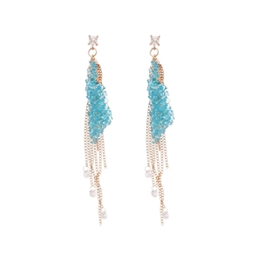 Elegant gold earrings with blue crystals, zircon studs and long chain tassels on white backdrop