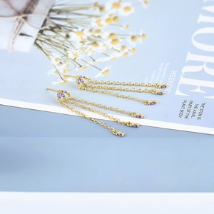 Detail of luxury gold chain tassel earrings with purple marquise cut crystals on blue card