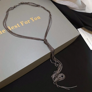Detail of multi-layered snake chain knot necklace with fringe tassel in gunmetal finish