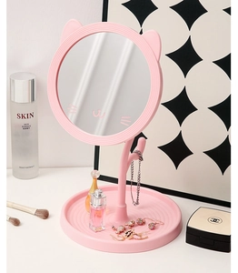 Pink cat-ear shaped makeup mirror with a round base tray on a vanity table