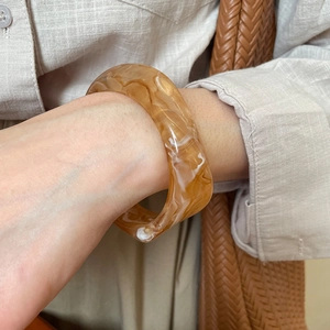 Close-up of amber marble resin cuff bracelet on model with natural earthy textures