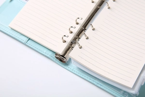 Detail of light blue PU leather binder with silver 6-ring mechanism and lined paper