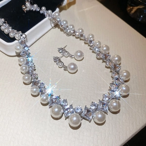Detailed view of diamond-encrusted pearl necklace and earrings set with starburst shimmer