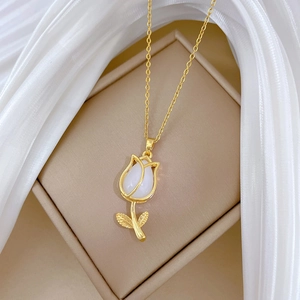 Elegant gold tulip necklace with white shell inlay pendant on a beige jewelry box
