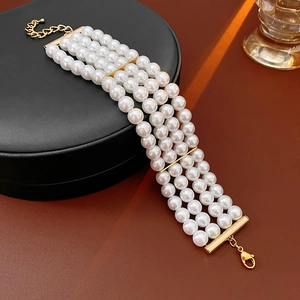 Vue détaillée d'un bracelet de perles à quatre rangs avec barres dorées et fermoir mousqueton