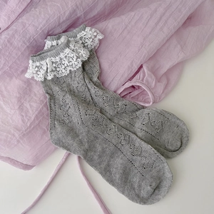 Detail of grey knitted ankle socks featuring elegant white lace trim and hollowed mesh texture