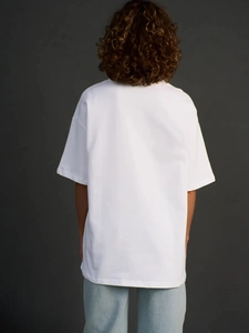 Πίσω όψη λευκού υπερμεγέθους βαμβακερού t-shirt με χαμηλωμένους ώμους και μινιμαλιστικό σχέδιο