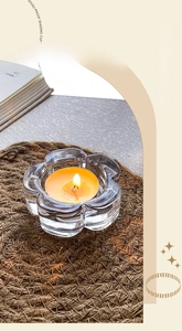 Detail of flower-shaped glass candle holder with yellow tealight on woven mat