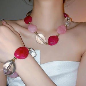 Close-up of pink and clear acrylic oval beaded necklace and bracelet set on a model