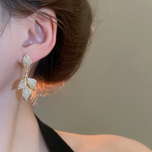 Detailed close-up of gold leaf-shaped tassel earrings with sparkling cubic zirconia stones