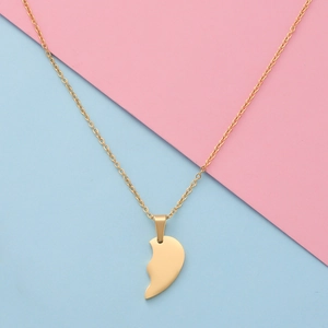 Detailed view of the gold split heart pendant with a fine cable chain on a pink background