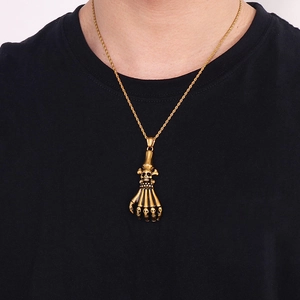 Detailed view of gothic gold skeleton hand pendant on twist chain for men