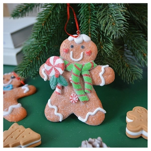Close-up of a gingerbread man ornament with red and green scarf hanging on a Christmas tree
