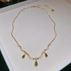 Dettaglio macro della collana placcata oro con pietra a goccia verde e piccoli zirconi