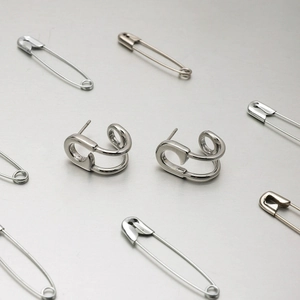 Detailed view of silver stainless steel paperclip earrings on a brushed metal background