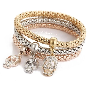 Detailed view of skull charms with rhinestones on three-tone popcorn chain bracelets