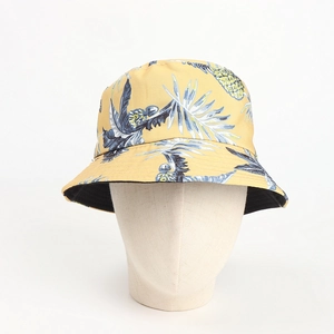 Detailed pattern of a yellow tropical bucket hat featuring blue palm leaves and pineapples