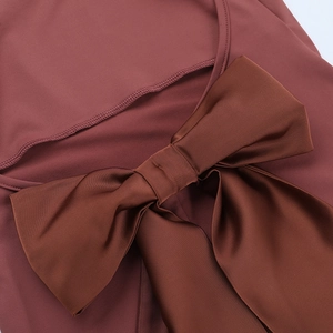 Détail d'un grand nœud en satin marron au dos d'une robe de soirée dos nu rose poudré
