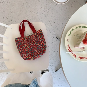 Detail of floral corduroy tote bag showing red fabric handle and metal magnetic snap closure