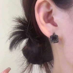 Detaillierte Makroansicht von schwarzen quadratischen Vintage-Ohrsteckern mit Strass.