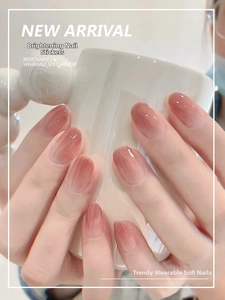 Close-up of glossy blush gradient oval press-on nails shown on hand holding a cup