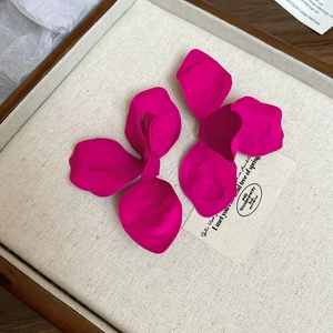 Detailed view of vibrant rose red floral petal earrings on a neutral display tray