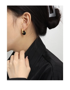 Primer plano de pendientes de plata S925 con aro dorado y colgante circular negro en modelo