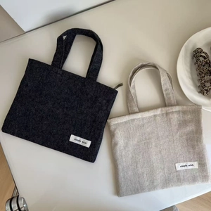 Detail of minimalist denim canvas handbags in dark grey and light beige with woven labels