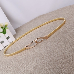 Dettaglio di cintura sottile dorata elastica con fibbia intrecciata per abiti da donna