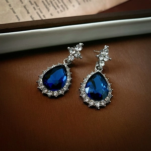Macro shot of silver drop earrings with blue pear-cut stones and zircon halo detail