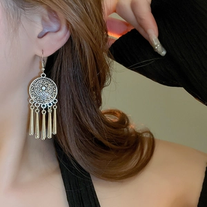 Close-up of vintage silver ethnic earrings with embossed patterns and metallic tassels