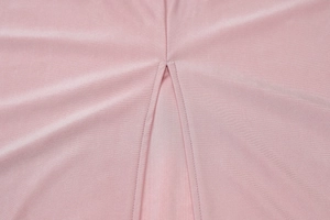 Dettaglio di un abito in maglia rosa con scollo a V e finiture a doppia cucitura