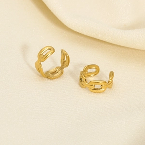 Detail of double-layered gold chain ear cuffs on beige fabric background