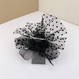 Detail view of the black mesh fascinator clip with polka dots, feather and metal clip