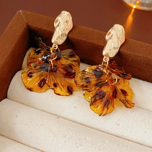 Detail of amber tortoiseshell petal earrings with gold textured studs in a jewelry box