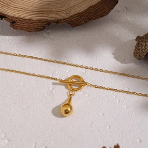 Minimalist gold teardrop pendant necklace with OT toggle clasp on a natural stone base