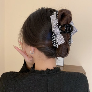 Detail of a large checkerboard and rhinestone bow hair claw clip for a chic hairstyle