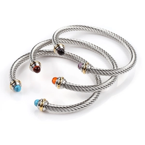 Detail of three twisted cable bracelets featuring colorful gemstone end caps on gold rings