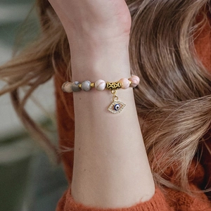 Beaded evil eye charm bracelet with pink marble stones and gold accents worn on wrist