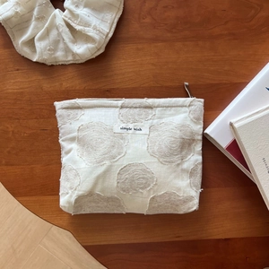 Detail of floral texture on cotton linen makeup pouch with simple wish label on wood