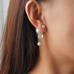 Close-up of double pearl earrings with square crystal pendant on a female model