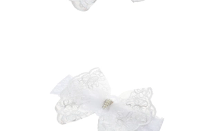 Detailed close-up of a white lace baby headband with pearl and rhinestone bow details