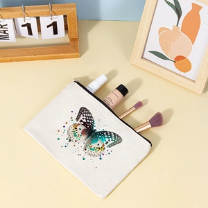 Canvas makeup pouch with butterfly print and black zipper on a cozy wooden desk setup